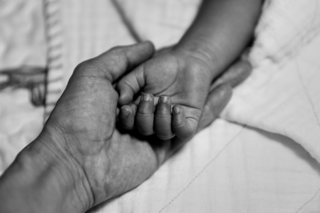 mother and daughter holding hands on pastel blanket as a backgro